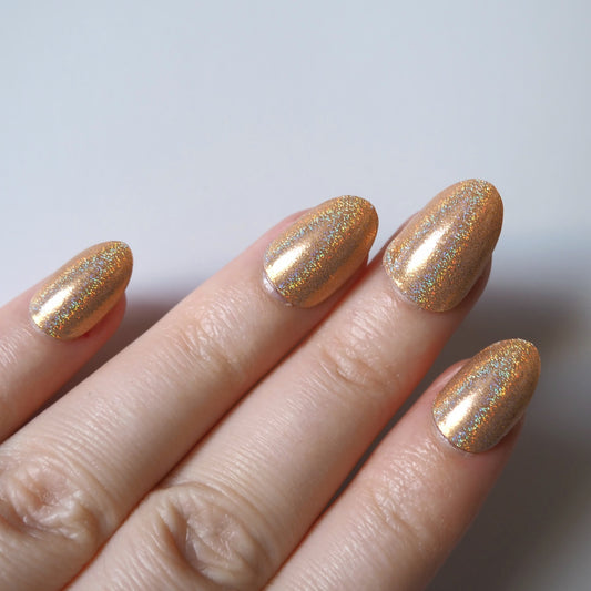 Gold glitter Pixie Dust nail wraps applied to natural nails viewed top down.
