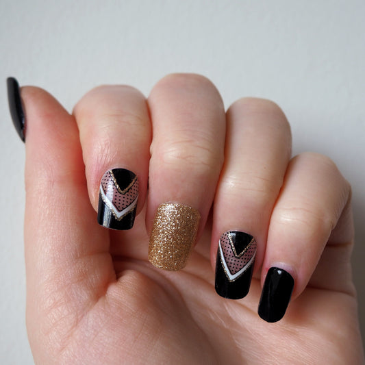 Peak through to the natural nail with these semi-transparent gold and white chevron accents on a black base.